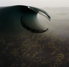 a large wave in the ocean on a foggy day