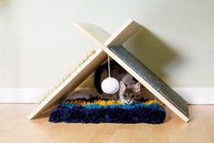 a cat is playing with a ball in the corner of a wooden structure on the floor