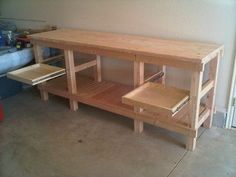 a table made out of wood sitting on top of a cement floor next to a red trash can