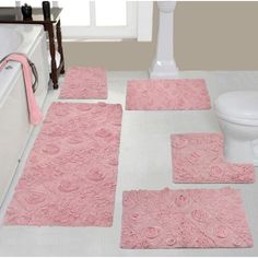 a bathroom with pink rugs and bath mats on the floor next to a toilet