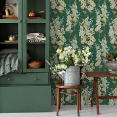 a green cabinet with flowers on it next to a wooden table