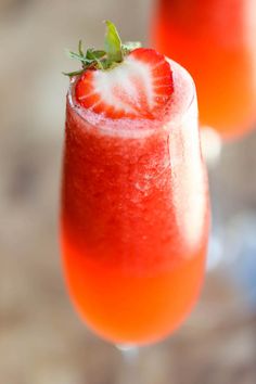 two wine glasses filled with red liquid and topped with a strawberries garnish