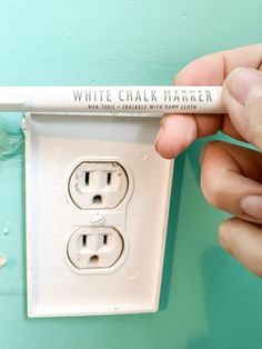 a person is holding a white chalk marker in their left hand and plugged into an electrical outlet