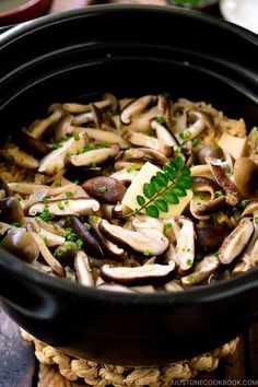 mushrooms and parsley in a black crock pot on a wooden table with other food items