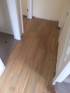 an empty room with hard wood floors and white trim on the door, next to a doorway