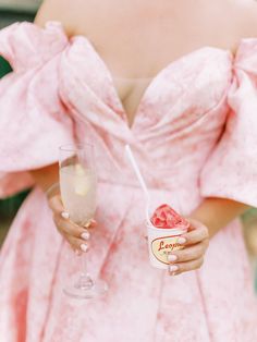 a woman in a pink dress holding a wine glass and a strawberry ice cream sundae