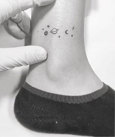 a person with a small tattoo on their ankle that has the planets and stars in it