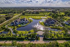 an aerial view of a large home surrounded by trees and water in the foreground