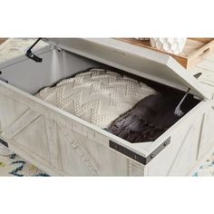 an open storage box filled with blankets on top of a rug