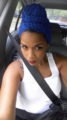 a woman sitting in the back seat of a car with a blue headband on