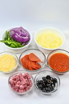 six bowls filled with different types of food on top of a white countertop next to green beans and red onions