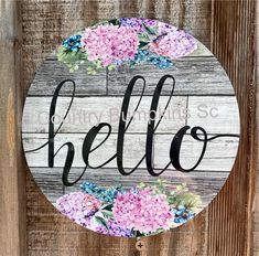 a wooden sign that says hello with pink and blue flowers on the front of it