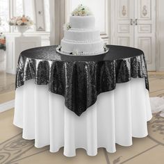 a white and black wedding cake on top of a table in a room with chandelier