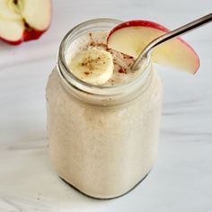 an apple and banana smoothie in a mason jar with a spoon on the side