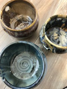 three bowls sitting on top of a wooden table filled with water and rocks in them