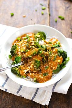 a white bowl filled with broccoli and other food on top of a wooden table