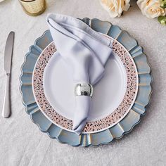 a place setting with silverware, napkins and flowers on a white table cloth