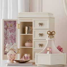 a white dresser with pink and gold accessories