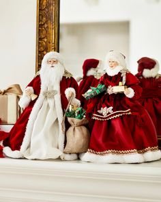 two santa clause figurines sitting on top of a mantle next to a mirror