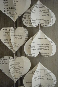 paper hearts hanging from strings with words written on them and attached to the strings are folded in different directions