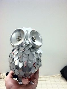 an owl made out of cans sitting on top of a bed