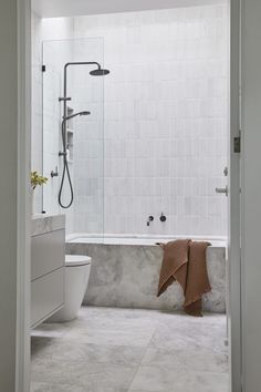 a bathroom with a bathtub, toilet and shower head mounted to the side of the wall