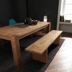 a wooden table with two benches next to it on a rug in front of a window