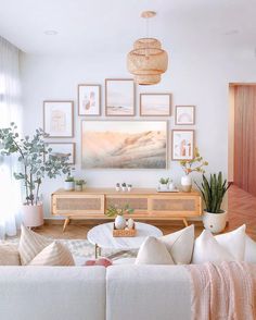 a living room filled with white furniture and pictures on the wall above it's coffee table