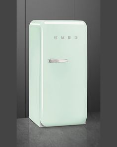 a white refrigerator freezer sitting on top of a counter next to a gray wall