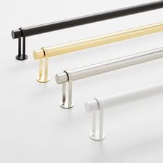 three different metal and wood bars on a white background, one is black, the other is gold