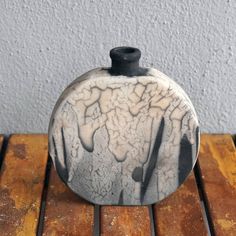 a black and white vase sitting on top of a wooden table