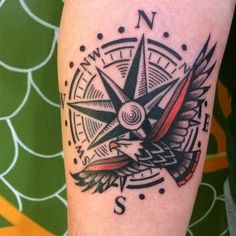 a compass tattoo on the leg of a person with an eagle and bird around it