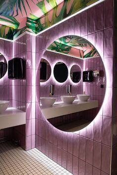 a bathroom with three sinks, mirrors and lights on the wall above them are palm leaves painted on the ceiling