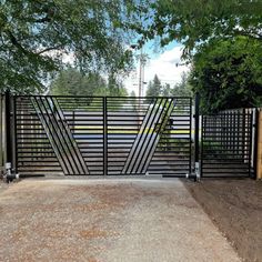 a gated driveway with trees and dirt in the foreground