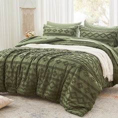 a bed with green comforters and pillows in a room