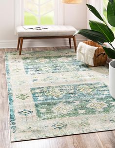 an area rug with a green and blue design on the floor in front of a window