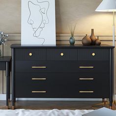 a black dresser with two vases and a painting on the wall next to it