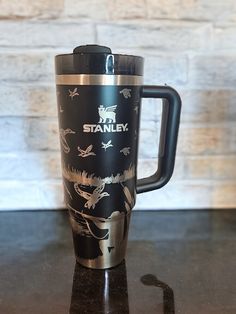 a black and silver travel mug sitting on top of a table