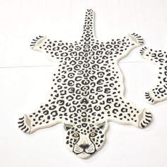 a white and black animal rug with leopard spots on it's back legs, in the shape of a cross