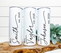 three personalized water bottles sitting on top of a wooden slab