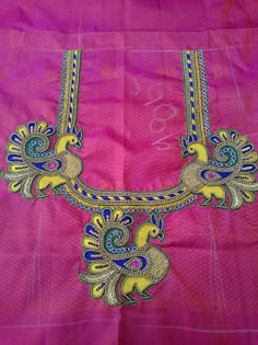 a pink blouse with gold and blue designs on the chest, along with an intricate necklace