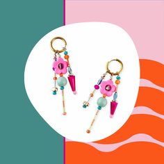 two key chains with flowers and beads hanging from them on an orange, pink background