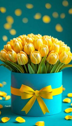 yellow tulips are in a blue vase with a bow on the top and confetti scattered around