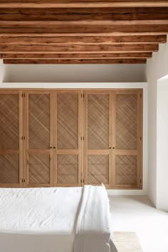 the bed is made up with white linens and wooden slats on the headboard