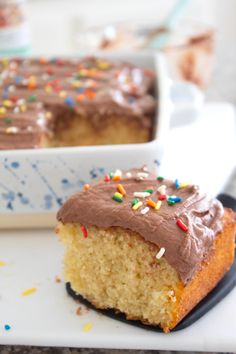 a piece of cake with chocolate frosting and sprinkles sitting on a plate