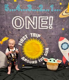 a baby standing in front of a sign that says one first trip around the world