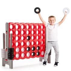 a young boy holding two giant black and white discs in front of a red board game