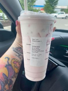 a person holding up a drink in their hand while sitting in the driver's seat