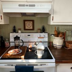 a stove top oven sitting inside of a kitchen next to a counter with pots and pans on it