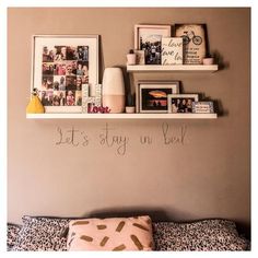 there are pictures on the wall above the bed and below it is a shelf that says, let's stay in bed